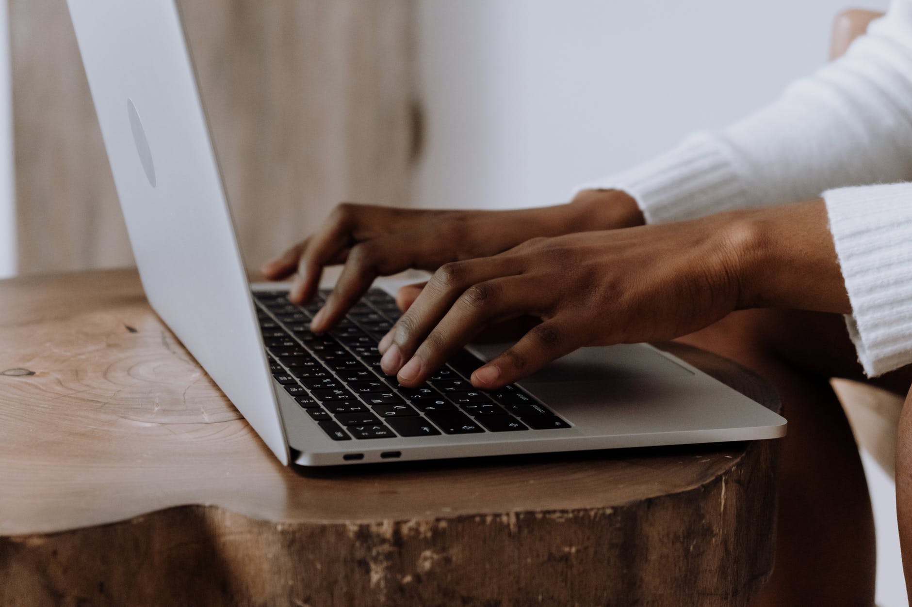 person using macbook pro on brown wooden table