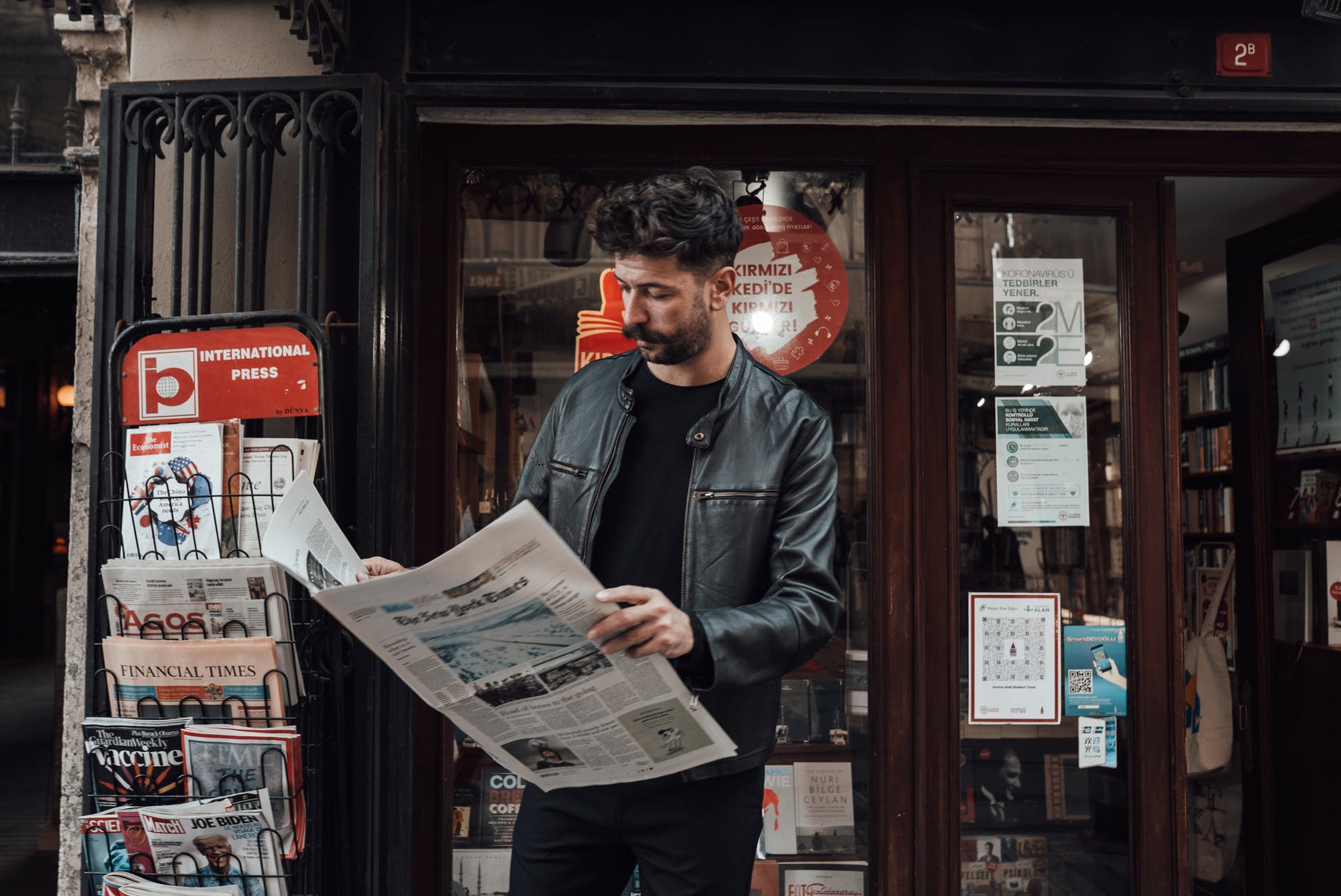 focused man reading newspaper on street